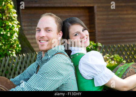 couple in traditional bavarian clothes leaning against each other Stock Photo