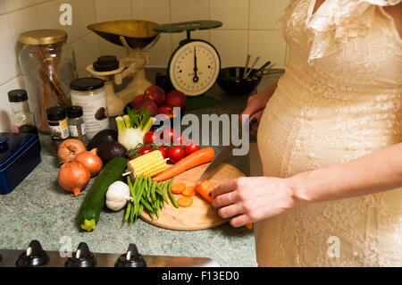 Pregnant woman slicing vegetables Stock Photo
