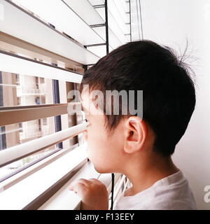 Portrait of a boy looking through the window