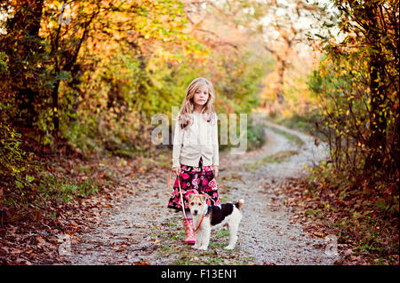 Girl walking her fox terrier dog in the woods Stock Photo