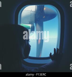 Girl sitting on a plane looking through window Stock Photo