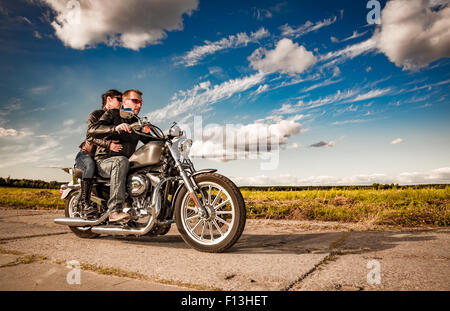 Couple Bikers in a leather jacket riding a motorcycle on the road Stock Photo