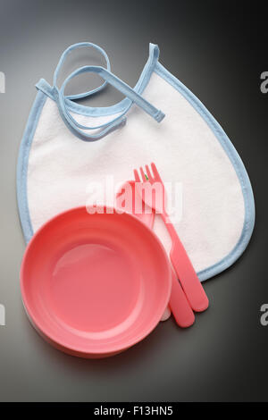 Bibs, bowl and spoon for baby in closeup Stock Photo