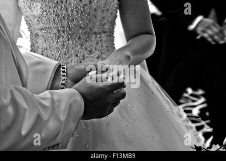 The groom placing the wedding ring on the brides finger during the wedding service. Stock Photo
