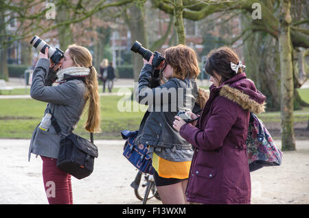 Three young girls taking photos in one of the parks in Amsterdam. Stock Photo