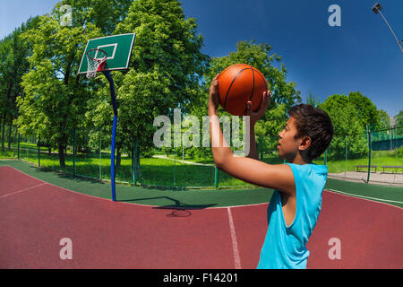 Arabian boy throwing ball in basketball goal Stock Photo