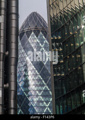 Stormy and sunny slkies light up the Gherkin and the lloyds Building in the City of London and St.andrew Undershaft Church Stock Photo
