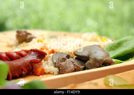 chicken liver and pork sausages served with green salad on wooden plate Stock Photo