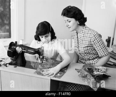 1950s 1960s MOTHER TEACHING DAUGHTER HOW TO SEW USING SEWING MACHINE Stock Photo