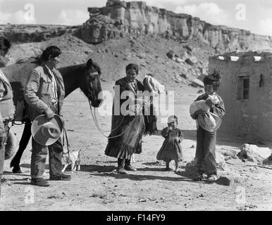 1930s NAVAJO NATIVE AMERICAN FAMILY AT THEIR ADOBE HOME MAN WOMAN MOTHER FATHER CHILDREN BOY BABY HORSE Stock Photo