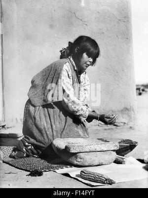 1930s NATIVE AMERICAN WOMAN GRINDING CORN ON STONE METATE SAN ILDEFONSO PUEBLO NEW MEXICO USA Stock Photo