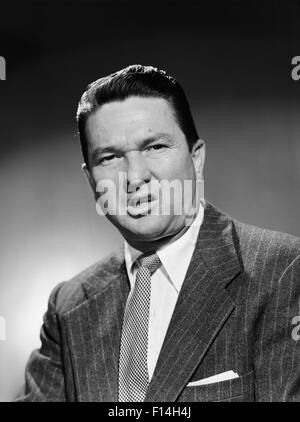 1950s BUSINESSMAN IN SUIT MAKING FUNNY SERIOUS FROWN FACIAL EXPRESSION SNEER DISGUST ANGER UNHAPPY ANGRY UNPLEASANT MEAN GROUCHY Stock Photo