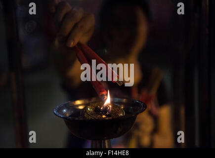 (150827) -- Hong Kong, Aug. 27, 2015 (Xinhua) -- A woman lights joss sticks during the eve of Ghost Festival at Kwun Tong in south China's Hong Kong, Aug. 26, 2015. In Chinese culture, the 15th day of the seventh month in the lunar calendar is called Ghost Day or Ghost Festival and the seventh month is regarded as the Ghost Month. In Buddhism, the Ghost Day is also called Ullambana (Yu Lan or Yu Lan Pen in pinyin). In Hongkong, the custom on Ullambana was introduced by Chaozhou (Chiu Chow in Cantonese) people about 100 years ago. They still mark the Ullambana Festival in accordance with their  Stock Photo