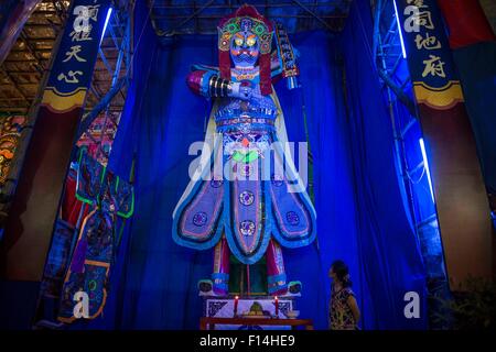 (150827) -- Hong Kong, Aug. 27, 2015 (Xinhua) -- A woman looks at a sculpture of ghost king, which is believed to be one of the embodiments of Bodhisattva Guanyin (Goddess of Mercy), the leader of wandering ghosts and spirits during the eve of Ghost Festival, at Kwun Tong in south China's Hong Kong, Aug. 26, 2015. In Chinese culture, the 15th day of the seventh month in the lunar calendar is called Ghost Day or Ghost Festival and the seventh month is regarded as the Ghost Month. In Buddhism, the Ghost Day is also called Ullambana (Yu Lan or Yu Lan Pen in pinyin). In Hongkong, the custom on Ull Stock Photo