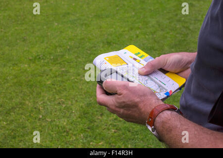 Man holding a GPS receiver and book with hiking routes n his hand. Stock Photo