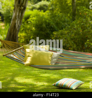 Bright stripy hammock and cushions in dappled sunlight Stock Photo