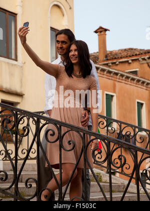 Italy, Venice, Young couple photographing themselves on stairs Stock Photo