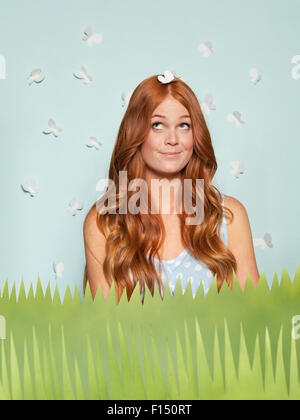 Young woman standing amidst paper grass surrounded by butterflies Stock Photo