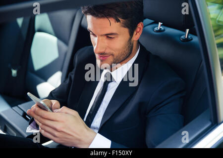 Handsome businessman using smartphone in car Stock Photo