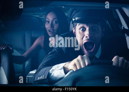 Male chauffeur with woman on back seat gets into car crash and makes ridiculous face Stock Photo