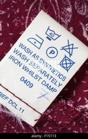 Care instructions label in red patterned dress - care washing symbols and instructions Stock Photo