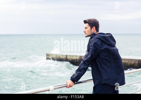 Young man in sports wear standing near sea outdoors Stock Photo