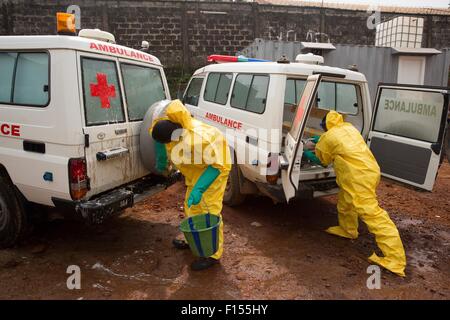 An ambulance drivers in protective clothing disinfect their ambulances with chlorine after returning from transporting a Ebola victim to a treatment center December 15, 2014 in Freetown, Sierra Leone. Stock Photo