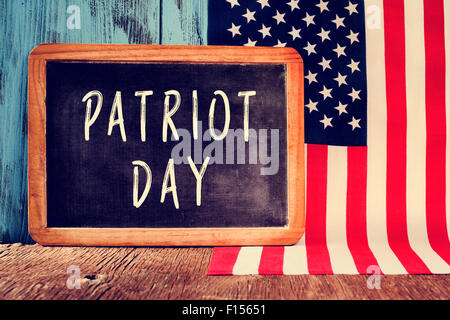the text Patriot Day written in a chalkboard and the flag of the United States on a rustic wooden surface Stock Photo