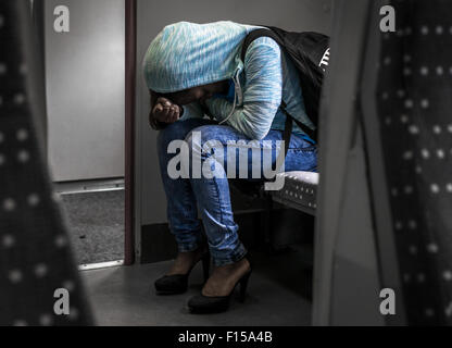 Single woman hangs her head in depression as she travels on a train to London Stock Photo