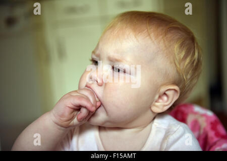 An eleven month old baby chewing on her hand to alleviate the pain and discomfort of tooth ache. Stock Photo