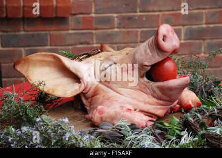A pigs head with a red apple stuffed in its mouth at a medieval style banquet. Stock Photo