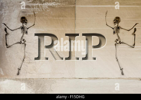 Engraved headstone spelling the letters RIP with Skeletons - rest in peace Stock Photo