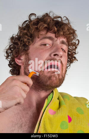 Scared curly haired man shaves off his beard Stock Photo