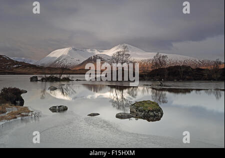 The lovely Black Mount snow capped mountain range with a frozen Lochan Na H-Achlaise in the foreground Stock Photo