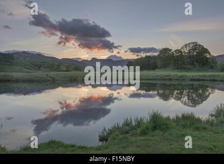 Langdale Pikes reflected in the River Brathay at dusk near Elterwater, English Lake District national park Stock Photo