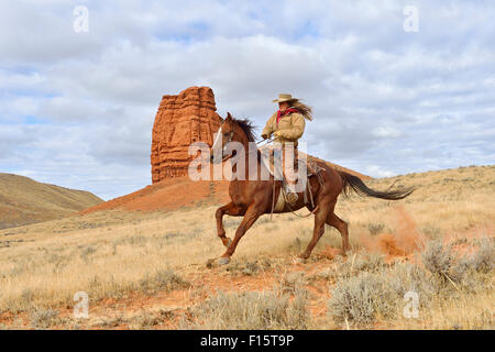 Cowgirl Riding Horse with Castel Rock in the background, Shell, Wyoming, USA Stock Photo
