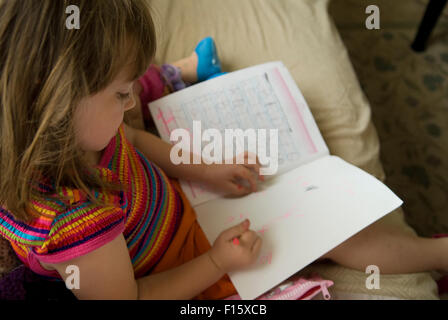 6 year old girl practicing writing skills in homework book Stock Photo