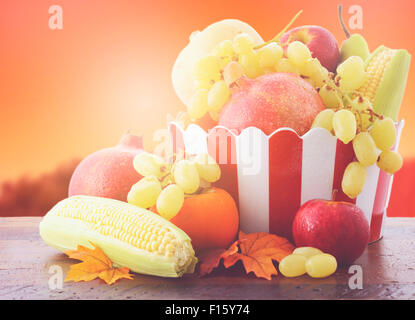 Bowl of Autumn fruit and vegetables on vintage wood table with Autumn sunset background, with added filters and lens flare. Stock Photo