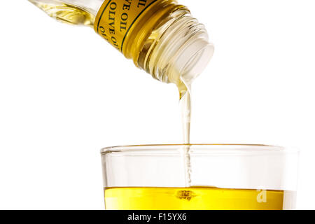 Pouring olive oil from bottle into glass Stock Photo