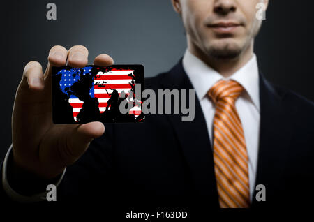 businessman in black costume and orange necktie reach out on camera and show credit card or visiting card, close up Stock Photo