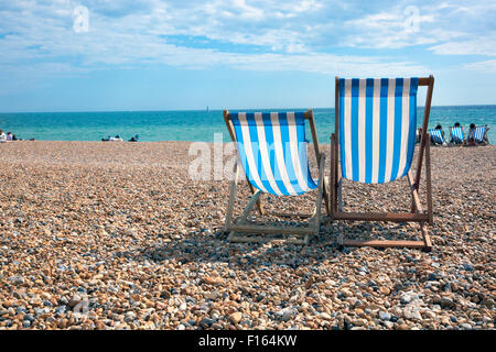 Two deck chairs on the beach facing sea, Brighton, UK Stock Photo