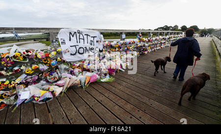 Shoreham, Sussex, UK. 28th August, 2015. A woman walking her dogs early this morning passes the thousands of floral tributes and messages which line the old toll bridge crossing the River Adur at Shoreham to remember those who died in the Shoreham Airshow disaster last weekend  It is almost a week after a Hawker Hunter jet flown by pilot Andrew Hill crashed on to the A27 during a display in the Shoreham Airshow killing 11 people  Credit:  Simon Dack/Alamy Live News Stock Photo