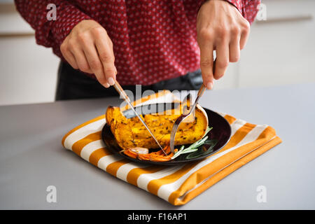 In closeup, an elegant woman's hands holding cutlery are picking food up or cutting it. Stock Photo
