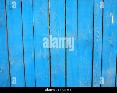 Fragment of a fence from wooden planks closeup, painted blue. The paint is partially peeled off. The fence is cracked. Stock Photo