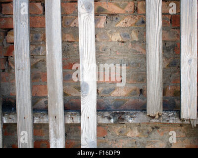Old wooden, unpainted and rotten boards with clearly visible structure of wood on a brick wall background Stock Photo