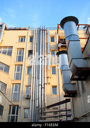 The back side of a multi-storey office building with pipes industrial ventilation, air conditioning and communications Stock Photo