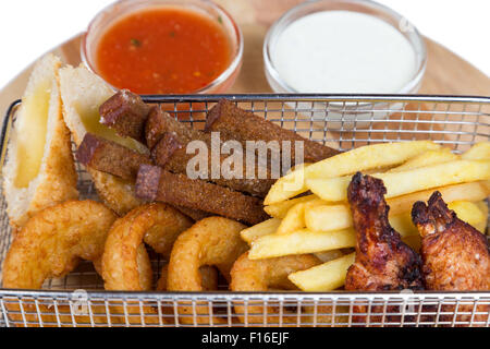 mix from snacks for beer in metal basket serving with sauces on wooden board Stock Photo