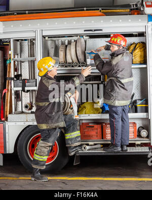 Male Firefighters Working At Truck Stock Photo