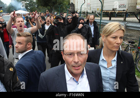 Heideau, Germany. 28th Aug, 2015. Saxony's interior minister Markus Ulbig (CDU, M) at a welcome party for refugees, while some of its attendees protest in the background, in Heideau, Germany, 28 August 2015. Credit:  dpa picture alliance/Alamy Live News Stock Photo
