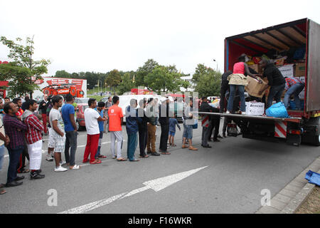 Heideau, Germany. 28th Aug, 2015. Refugees stand in line to collect donated items from a truck in Heideau, Germany, 28 August 2015. The welcome party was organised by Buendnis Dresden Nazifrei (lit. Dresden anti-Nazi league). Credit:  dpa picture alliance/Alamy Live News Stock Photo